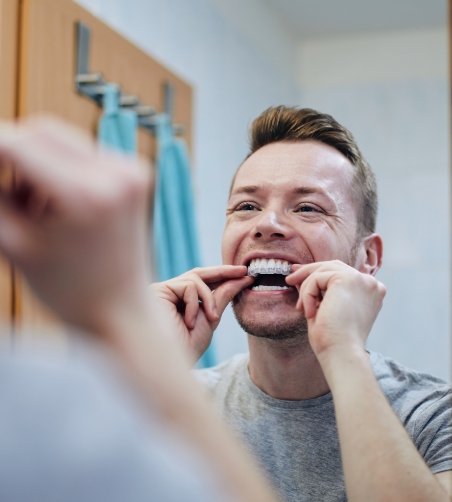 Man looking in mirror and putting in whitening tray