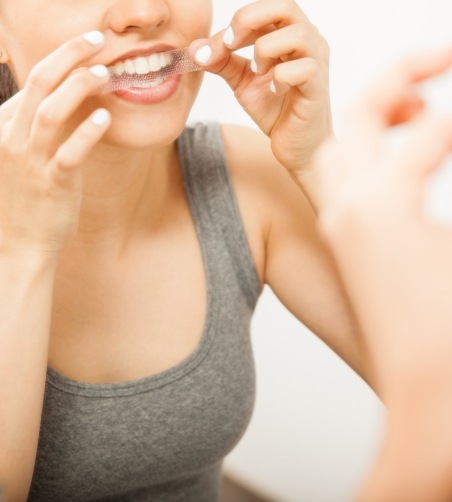 Woman in grey shirt using whitening strips