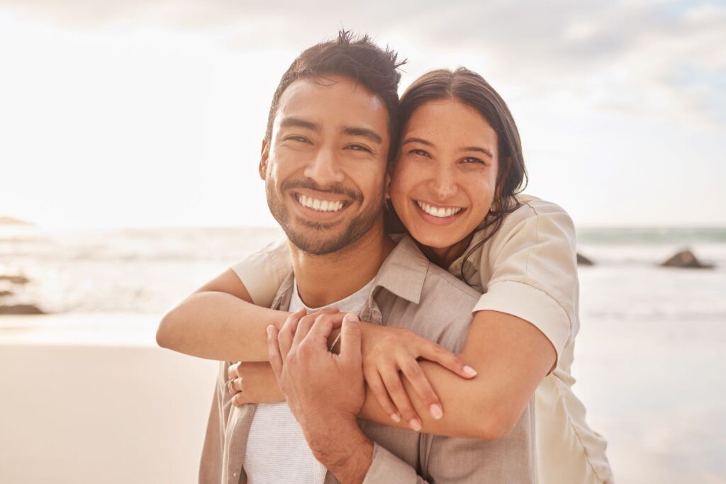 A couple smiling on the beach.