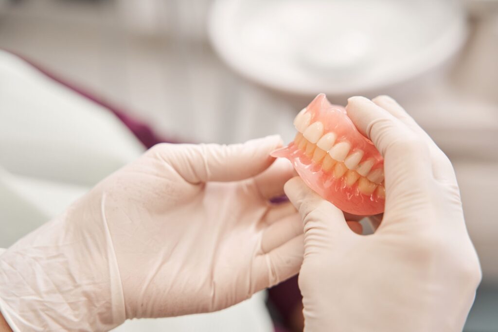 White-gloved hands holding a new set of complete dentures